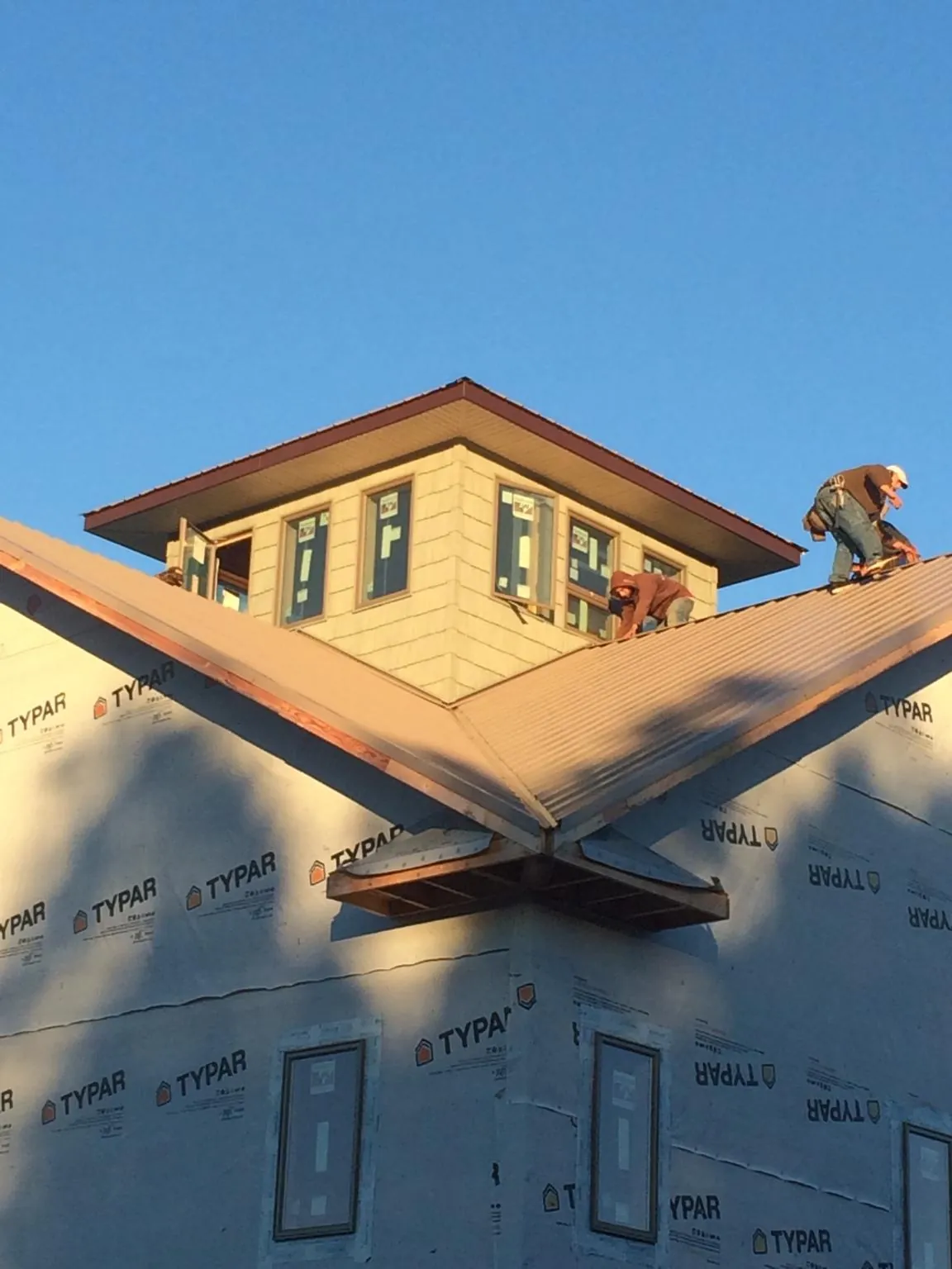 Roofers working around a rooftop cupola on a new metal roof at sunset — Roof Waterproofing in North Hampton by Roofing Brothers